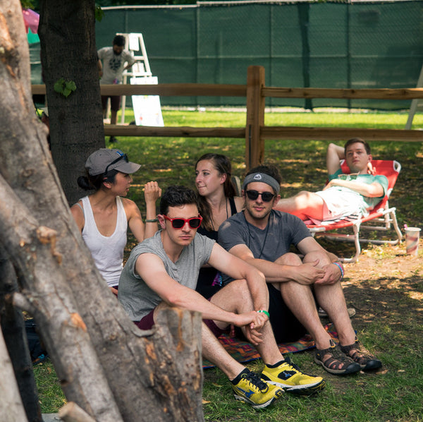 a group of people sitting in a park, with one wearing a headband